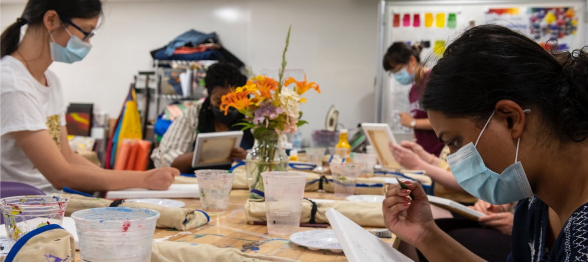 Students sit at a table in a room or space equipped for scientific experiments, research, and/or teaching.