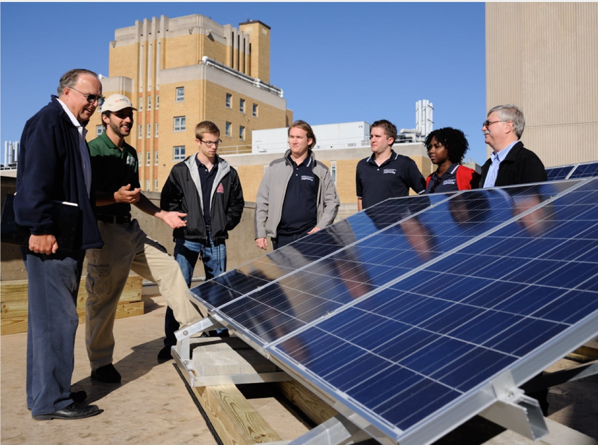 Group standing around rooftop solar panels