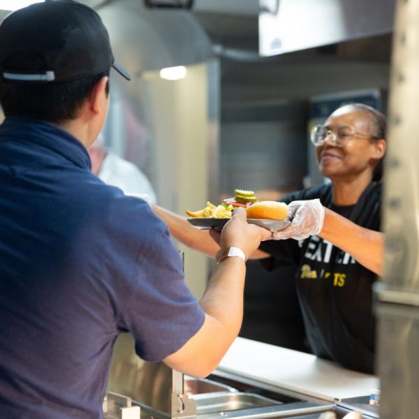 PittEat's staff member hands a meal to a student