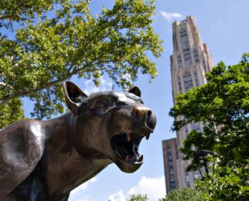 The Pitt panther statue with the Cathedral of Learning in the background.