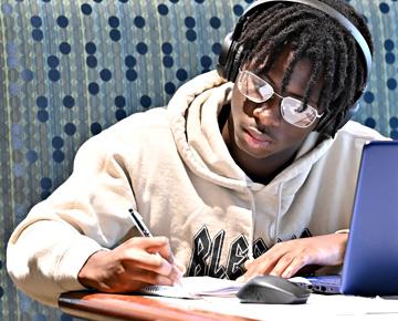 A young student studies while wearing headphones.