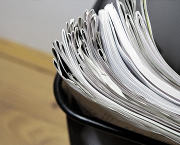 A stack of paper sits in a waste basket. 