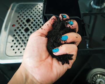 A person grasps composted materials in their hand.