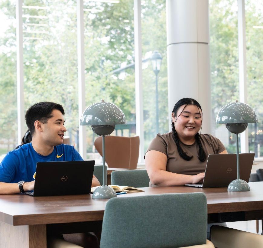 Two students sit at a table in HIllman Library