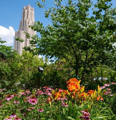 The Cathedral of Learning behind trees and flowers
