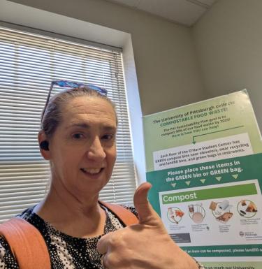 Suzanne Doolen giving a thumbs up in front of a compost sign