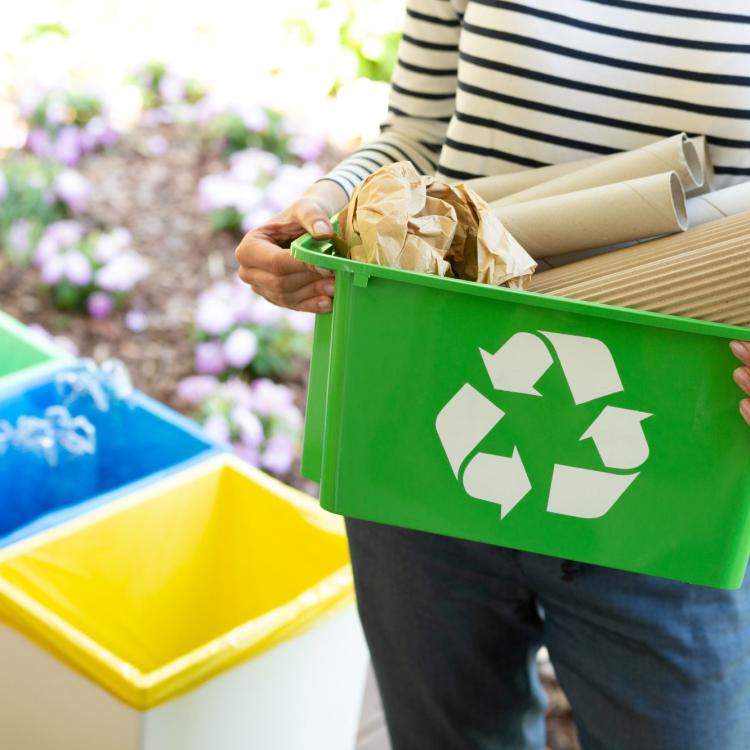 woman holds bin full of recycling