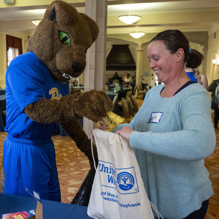 Roc the panther helps pack kits for United Way
