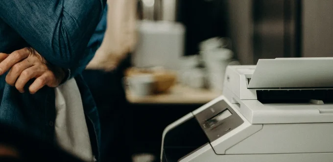 A worker stands at an office printer.
